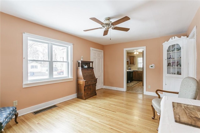 sitting room featuring ceiling fan, light wood-style flooring, visible vents, and baseboards