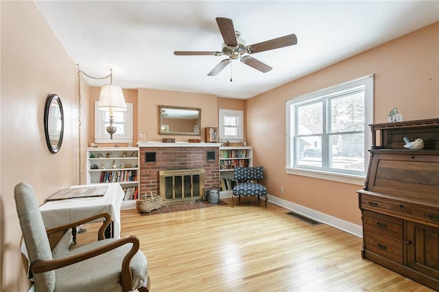 living area with visible vents, a fireplace, baseboards, and wood finished floors