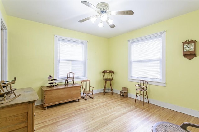 sitting room featuring baseboards, ceiling fan, and light wood-style floors