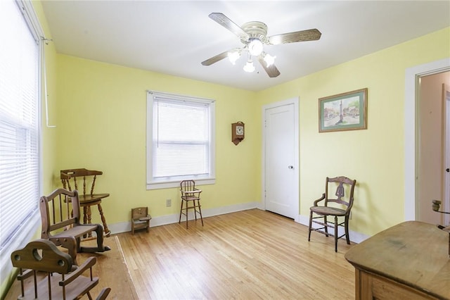 sitting room with light wood-style flooring, baseboards, and ceiling fan