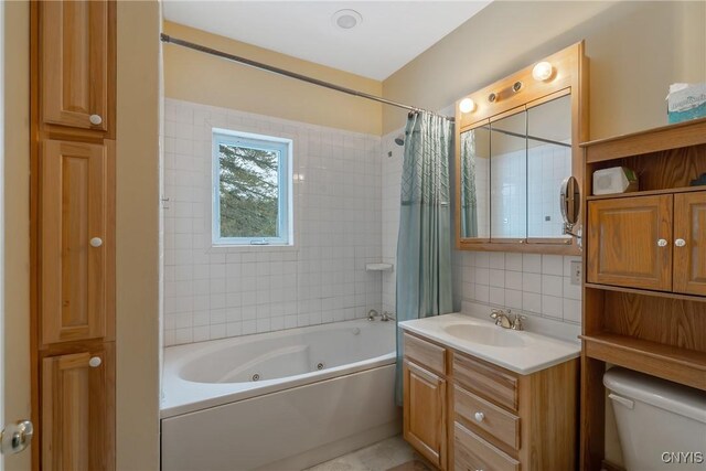 bathroom with a combined bath / shower with jetted tub, toilet, vanity, and decorative backsplash