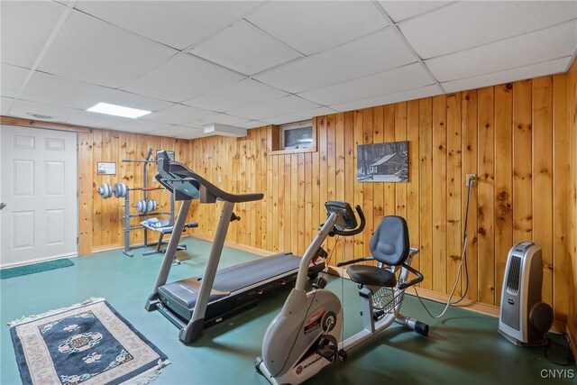 workout area featuring wood walls and a drop ceiling