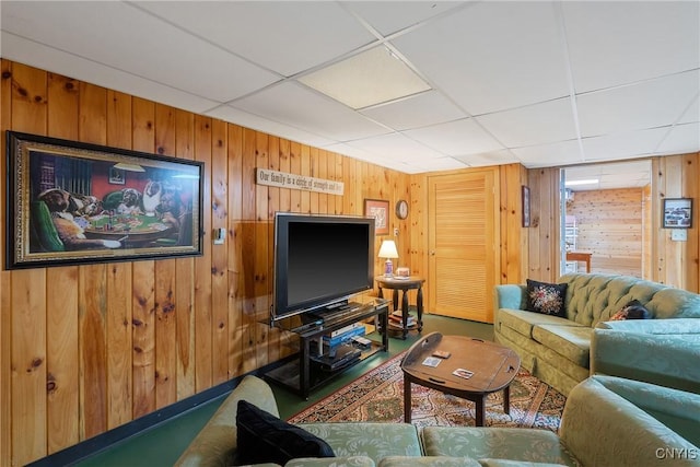 living room featuring a drop ceiling and wooden walls