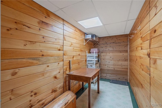 office space with a drop ceiling and wood walls