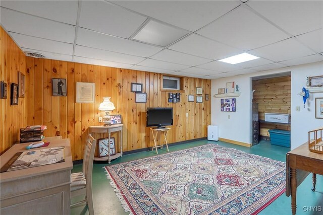 interior space featuring finished concrete flooring, wood walls, and a drop ceiling