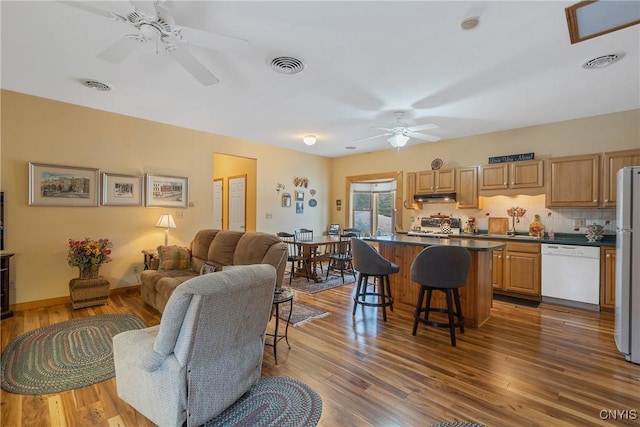 living room featuring a ceiling fan, visible vents, and wood finished floors