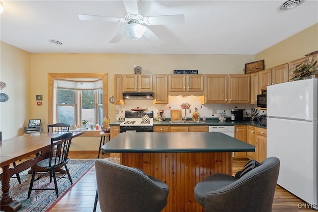 kitchen featuring white appliances, under cabinet range hood, visible vents, and a sink