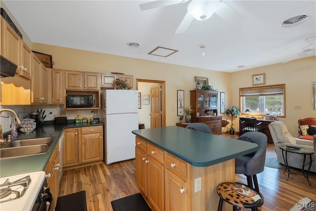 kitchen featuring visible vents, range, freestanding refrigerator, black microwave, and a sink