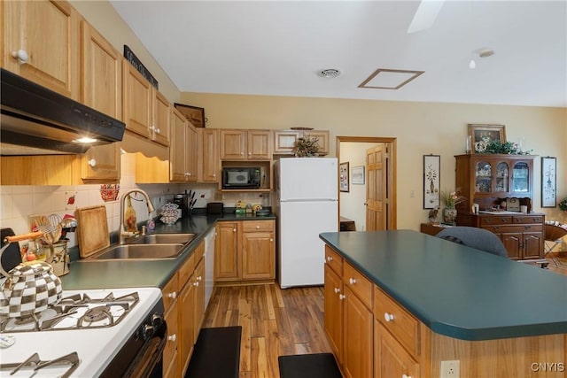 kitchen featuring white appliances, tasteful backsplash, light wood finished floors, dark countertops, and a sink