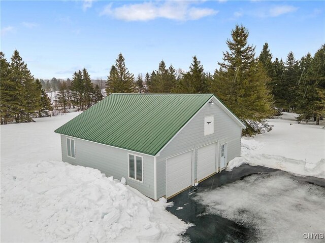 view of side of home featuring driveway and metal roof