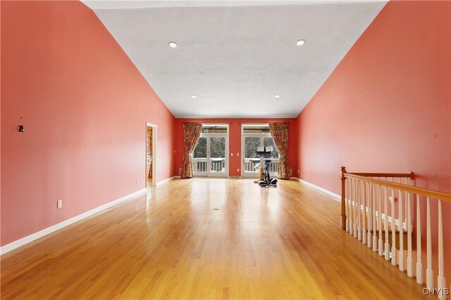 empty room featuring recessed lighting, wood finished floors, a towering ceiling, and baseboards