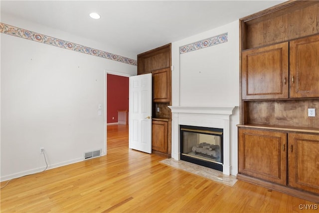 unfurnished living room featuring recessed lighting, a fireplace with flush hearth, visible vents, baseboards, and light wood-style floors