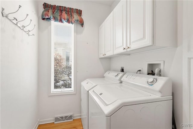 laundry area featuring washer and clothes dryer, cabinet space, visible vents, light wood-type flooring, and baseboards