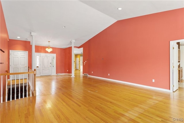 unfurnished living room with lofted ceiling, baseboards, light wood-style flooring, and ornate columns