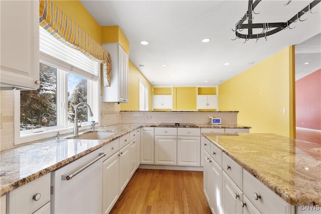 kitchen featuring light stone counters, a sink, white cabinetry, light wood-type flooring, and dishwasher