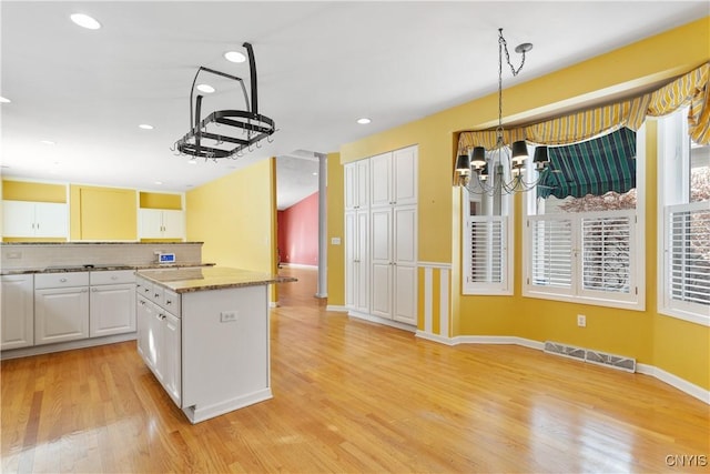 kitchen with decorative light fixtures, light wood finished floors, visible vents, and white cabinetry