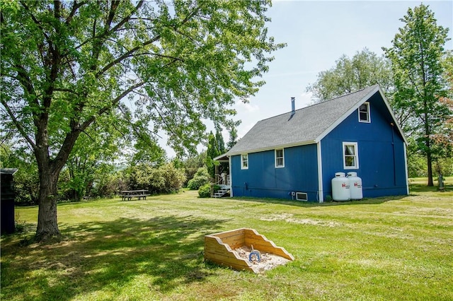 exterior space with a shingled roof and a lawn