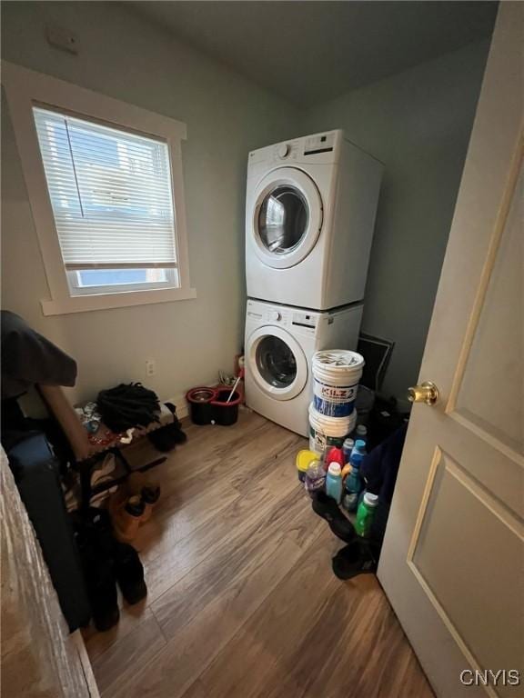 washroom featuring laundry area, wood finished floors, and stacked washer and clothes dryer