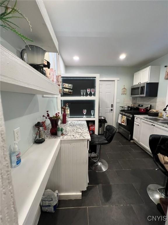 kitchen featuring light countertops, appliances with stainless steel finishes, a sink, and white cabinetry