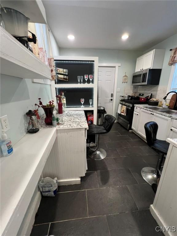 kitchen featuring stainless steel appliances, recessed lighting, light countertops, white cabinets, and a sink