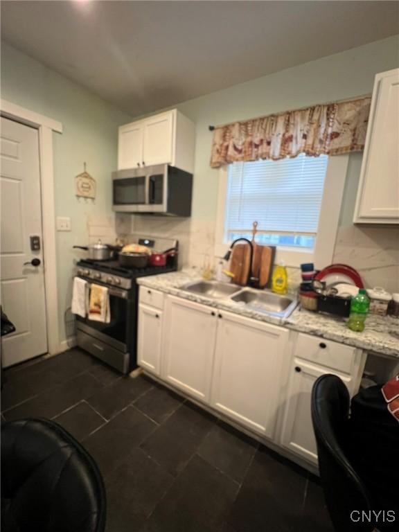 kitchen featuring a sink, white cabinetry, light countertops, appliances with stainless steel finishes, and decorative backsplash