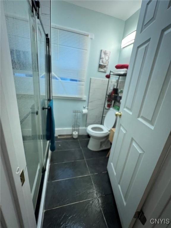 full bath with toilet, a stall shower, baseboards, and tile patterned floors