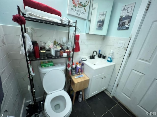 bathroom with toilet, tile patterned flooring, tile walls, and vanity