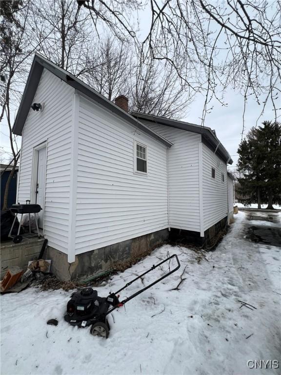 view of snow covered exterior with a chimney