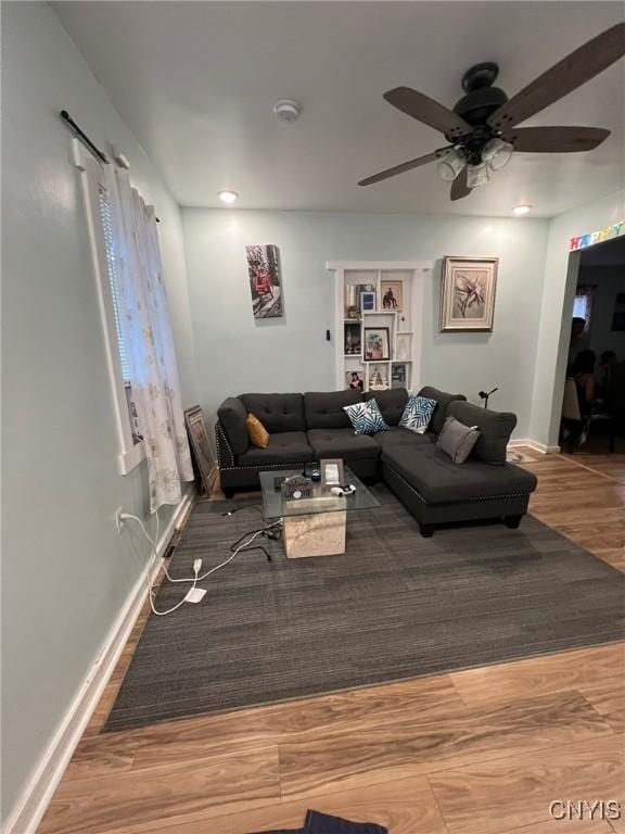 living area featuring a ceiling fan, baseboards, and wood finished floors