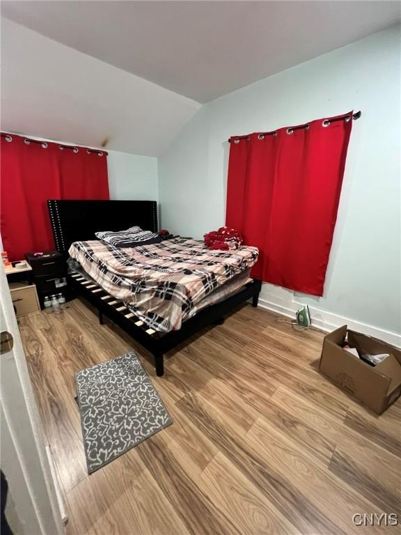 bedroom with lofted ceiling and wood finished floors