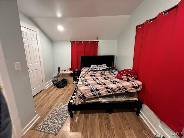 bedroom with lofted ceiling, wood finished floors, and baseboards