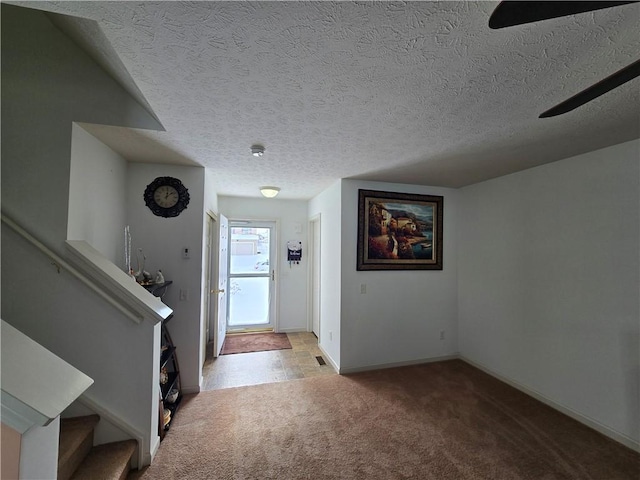 foyer with carpet floors, stairway, baseboards, and a textured ceiling