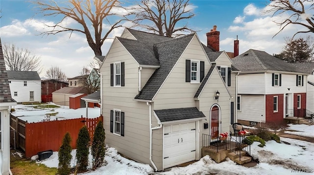 view of front of property featuring a shingled roof, fence, a chimney, and an attached garage