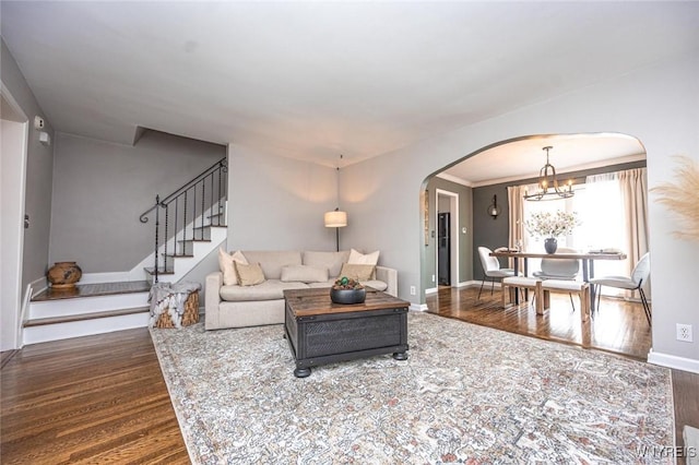 living room with baseboards, arched walkways, wood finished floors, stairs, and a chandelier