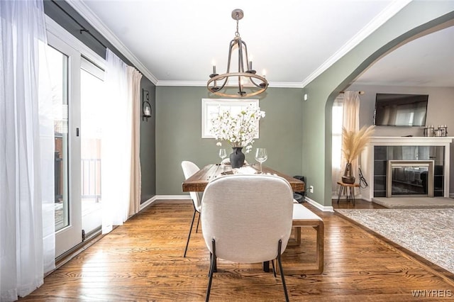 dining room featuring crown molding, arched walkways, and hardwood / wood-style floors