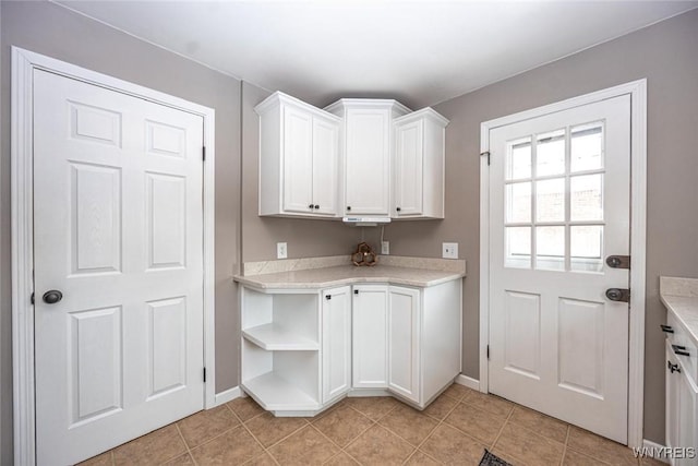 clothes washing area with light tile patterned floors and baseboards