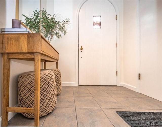 entryway featuring arched walkways, tile patterned flooring, and baseboards