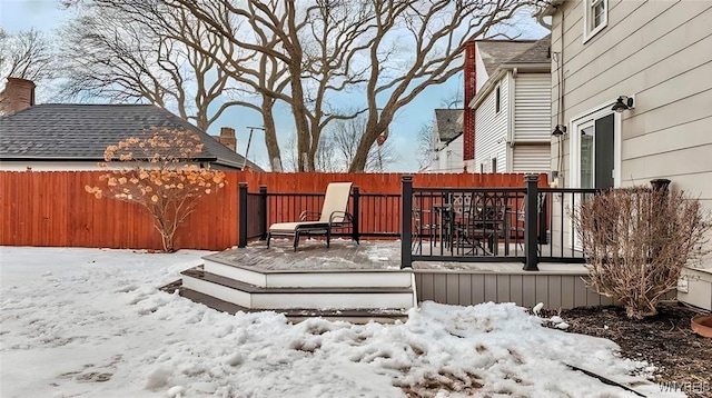 snow covered deck featuring a fenced backyard