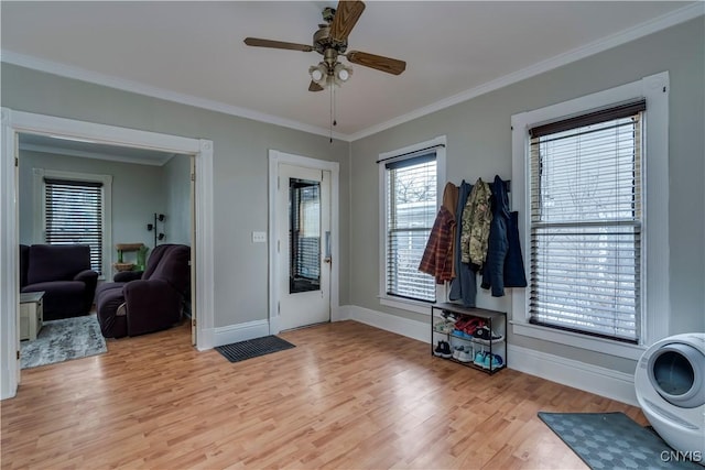 foyer featuring light wood finished floors, baseboards, ornamental molding, and a ceiling fan