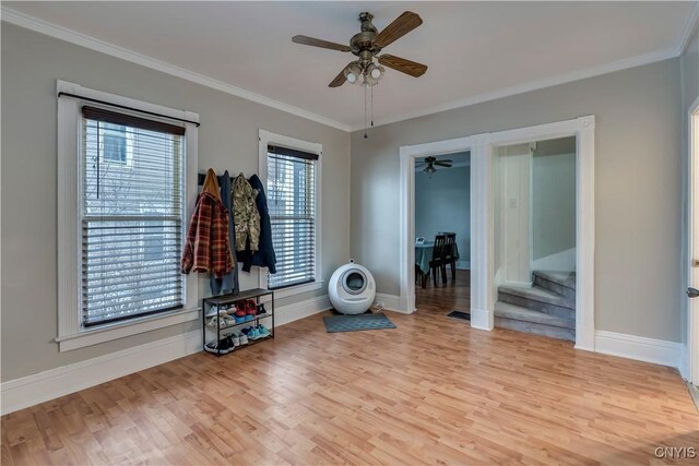 interior space featuring baseboards, wood finished floors, a ceiling fan, and crown molding