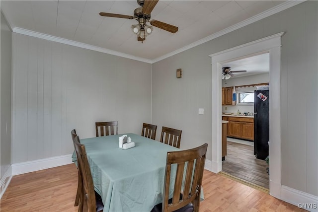 dining room featuring light wood-style flooring, a ceiling fan, and crown molding