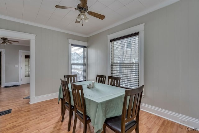 dining space with baseboards, visible vents, a ceiling fan, ornamental molding, and light wood-style floors