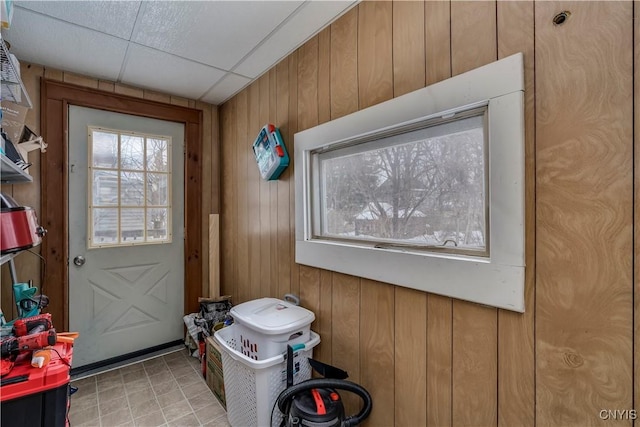 doorway with a paneled ceiling and wood walls