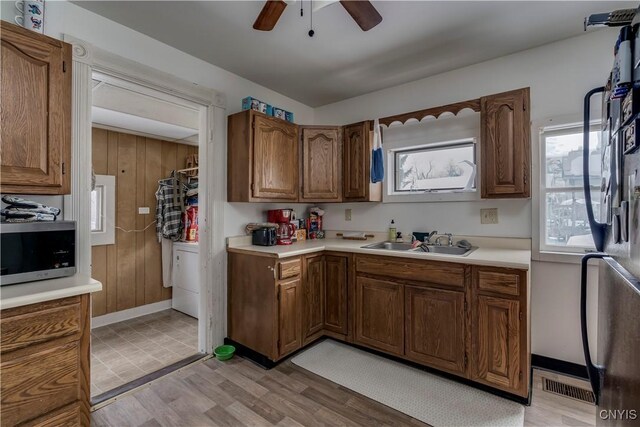 kitchen featuring light countertops, stainless steel microwave, a sink, and visible vents