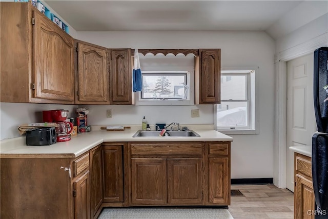 kitchen featuring brown cabinets, light wood finished floors, light countertops, and a sink