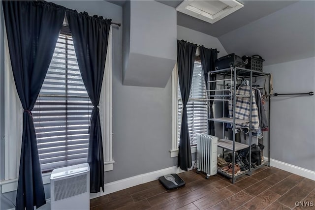 interior space with baseboards, radiator, lofted ceiling, a wall unit AC, and wood finish floors