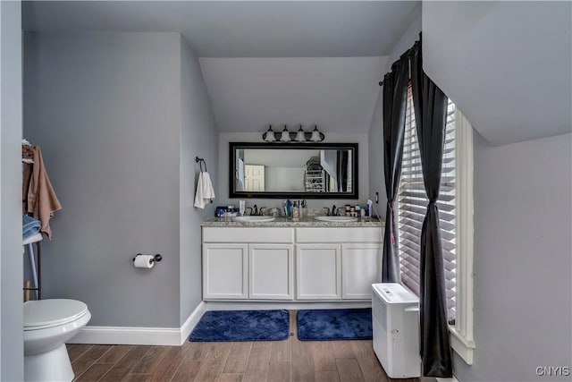 full bathroom featuring toilet, a sink, baseboards, and wood finished floors