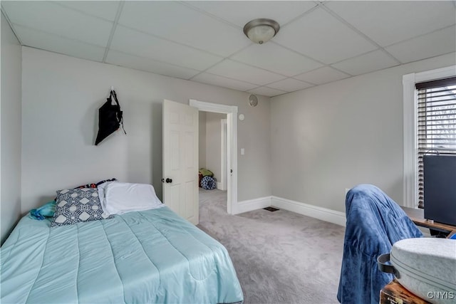 bedroom with carpet, a drop ceiling, and baseboards