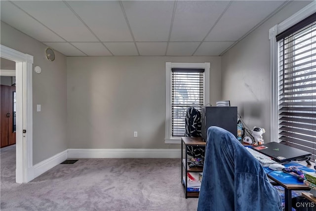 carpeted office space with a paneled ceiling and baseboards