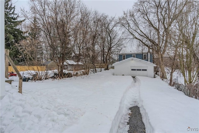 yard covered in snow with a garage, fence, and an outdoor structure